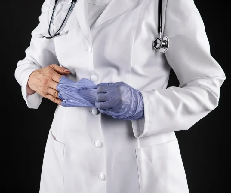 A doctor wearing gloves and a white coat, preparing for breast reduction surgery.