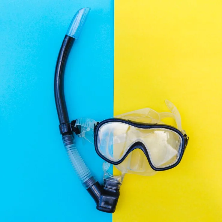 Diving mask and snorkel placed on a vibrant blue and yellow background, highlighting essential diving equipment for comfort and safety