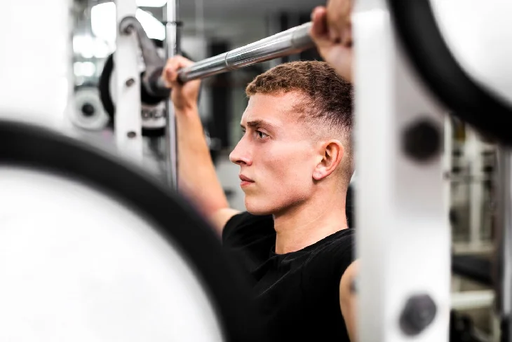 Muscular man using Smith Machine for squats, showcasing proper form and technique