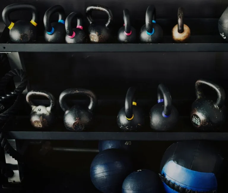 Kettlebells and medicine balls on a gym rack, essential equipment for strength training and muscle development.