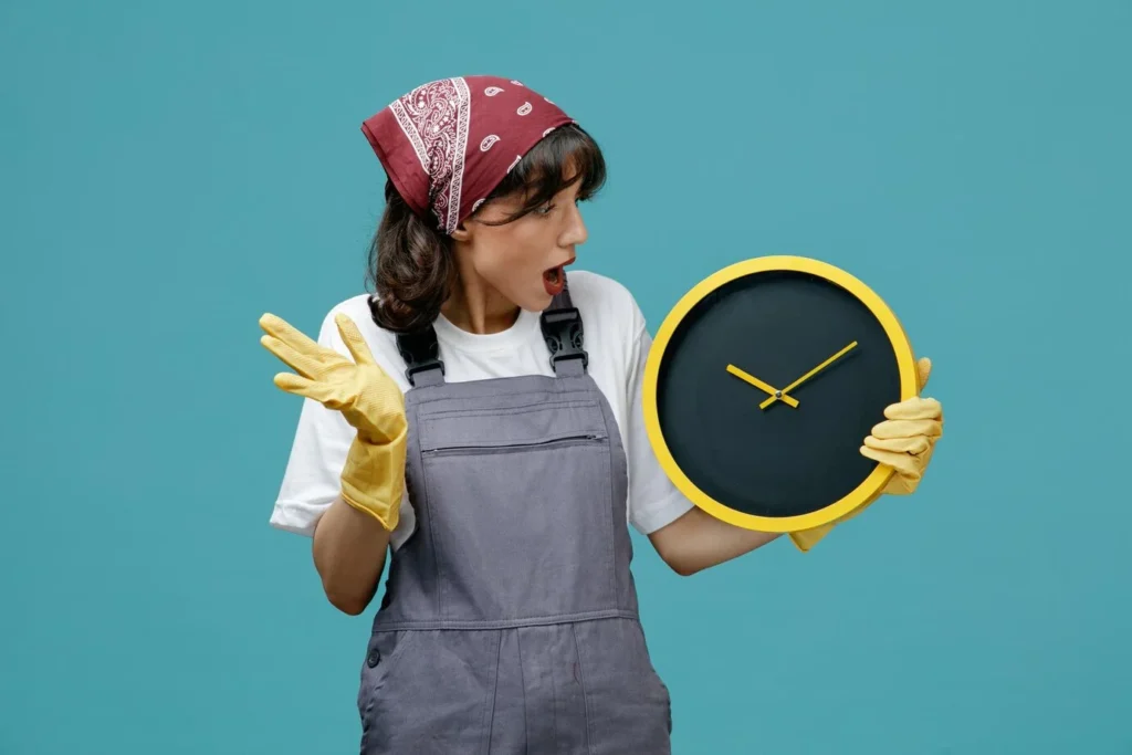 A professional cleaner wearing gloves and holding a yellow clock, emphasizing the time required for end-of-lease cleaning.