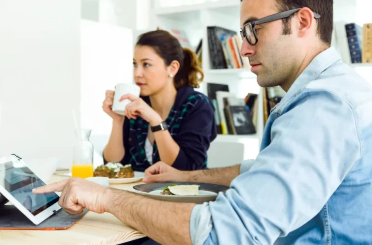 Professionals collaborating in an office, with one using a tablet and the other holding a coffee, representing e-learning solutions with Open edX service providers.