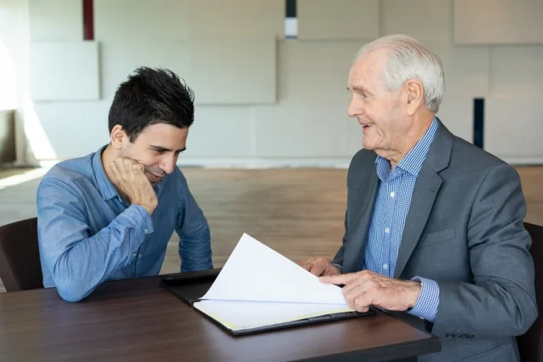 An experienced personal injury lawyer discussing legal documents with a client in an office.