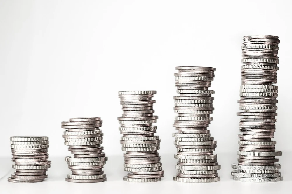 The image shows six stacks of silver coins, each progressively taller from left to right, representing the growth of personal injury compensation payouts.