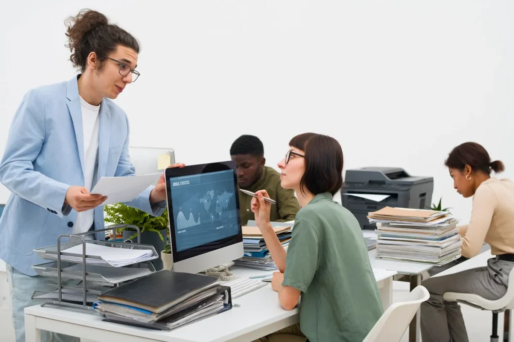 Business team collaborating around a digital knowledge management dashboard displaying search, analytics, and workflow features on a large screen